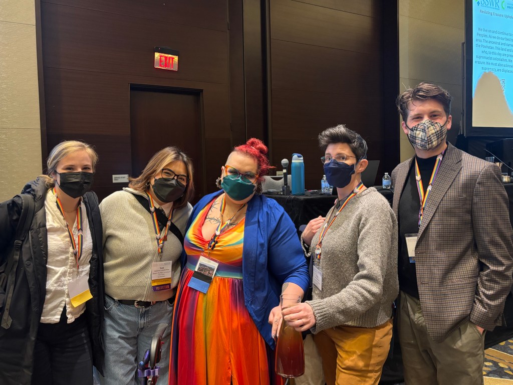 Image of 5 masked individuals standing in a hotel conference room